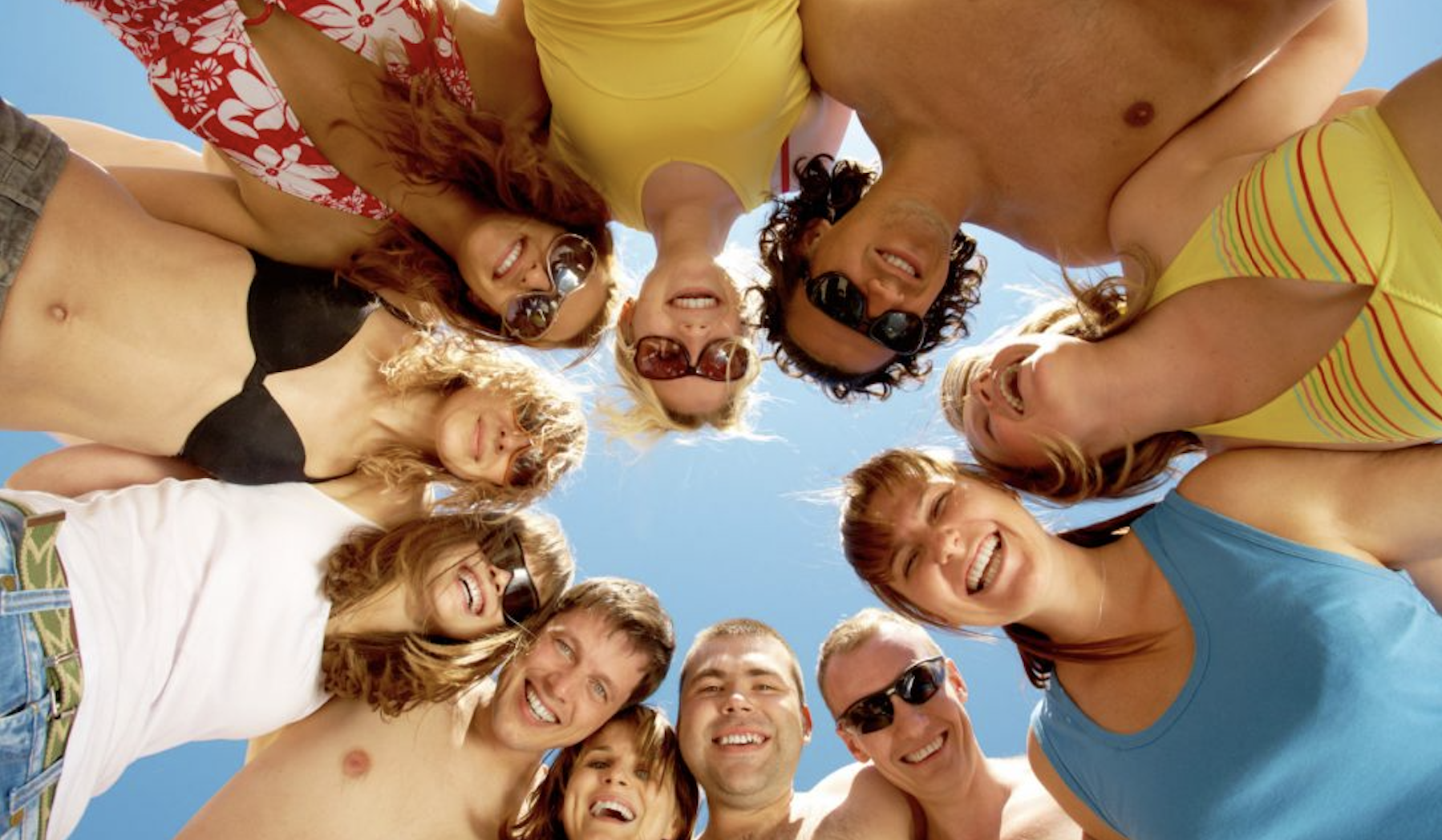 a group of friends on holiday huddled around smiling at the camera