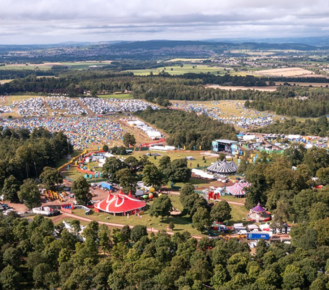 Drone Image of Kendal Calling Festival from above, sunny weather, with red big top tents, campsites and main stage in view.