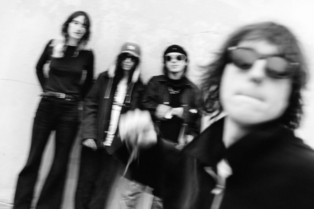 Geese band members pose for a press shot, with lead singer punching the lens