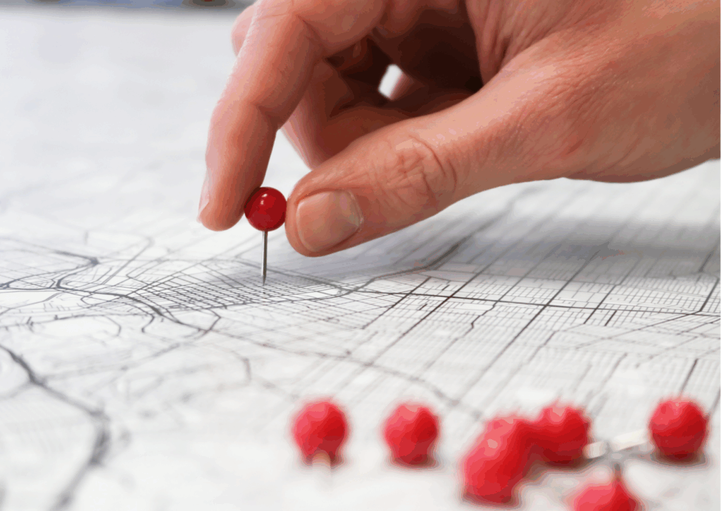 A hand putting a push pin in a map