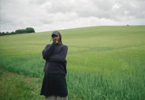 Dev Hynes, AKA Blood Orange, stood in a green field.