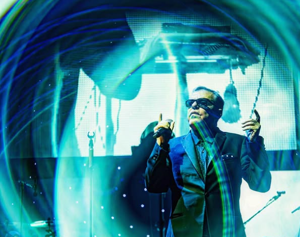 Picture of lead singer from the band Madness, onstage. The camera has used light in an interesting, distorted way where blue ribbons of light circle the singer.