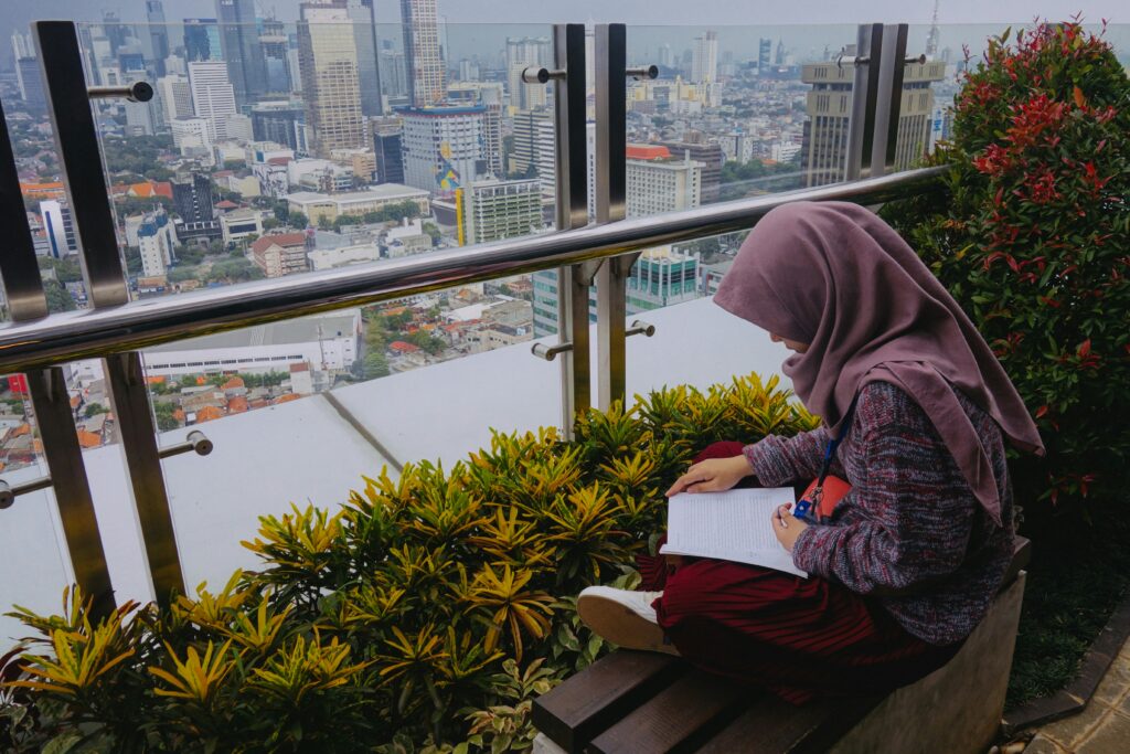Hijabi woman reading in front of a window