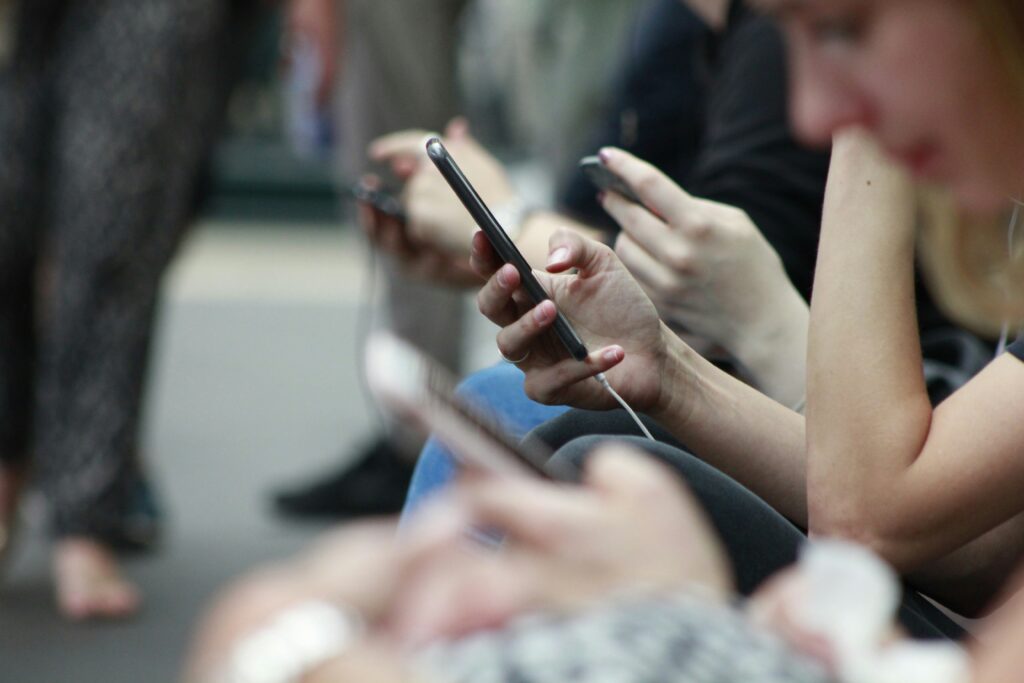 people scrolling on phones in a train station