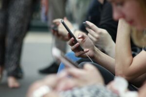 people scrolling on phones in a train station