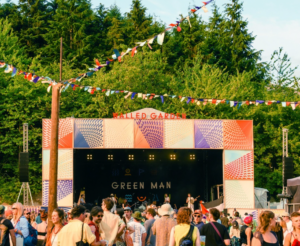 Sunny photo of the Walled Garden stage at Green Man Festival. There is a crowd in the foreground, presumably waiting for the next act. Bunting is hung from the stage.